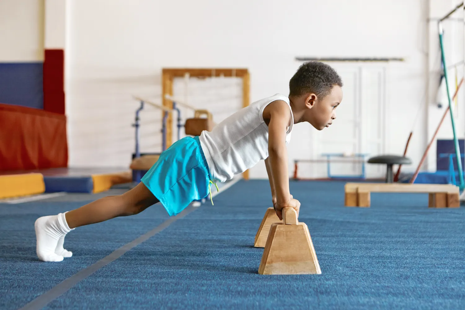 Sideways shot of concentrated serious afro american kid in sports clothes keeping feet on floor<br />